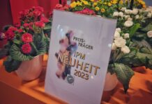 Nagrodzone kwiaty na targach IPM Essen. KOlorowe kwiaty i tablica informująca o przyznanej nagrodzie